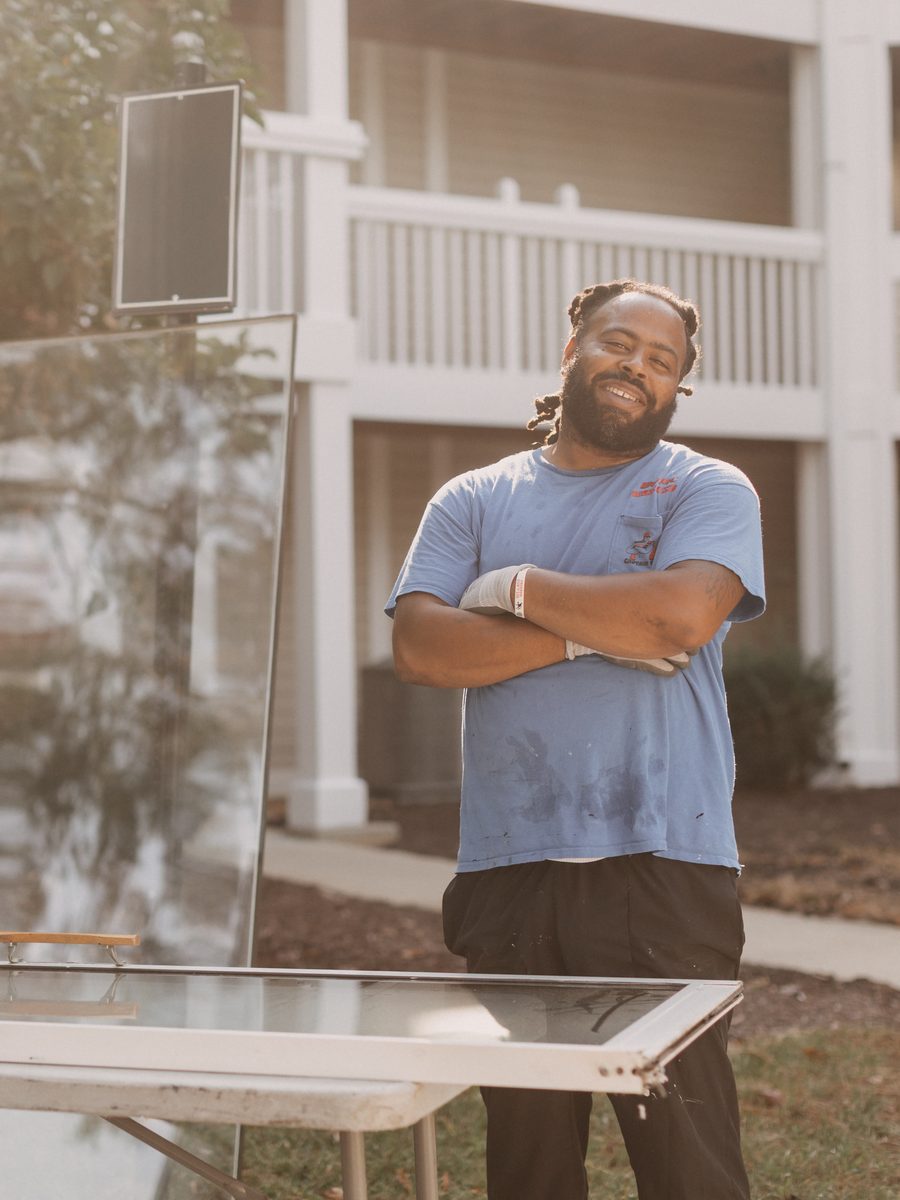 Budget Glass Company technician standing beside new glass on a job site at an apartment building
